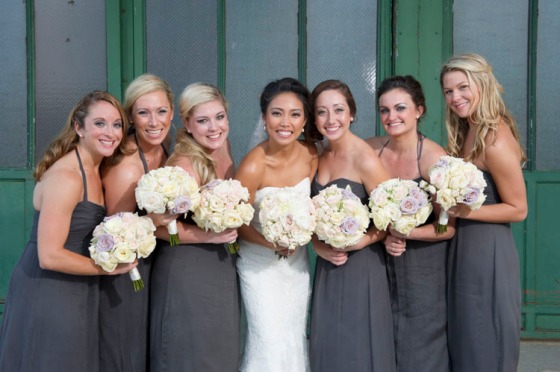 Bridesmaids wearing gray dresses and blush white bridesmaids bouquets